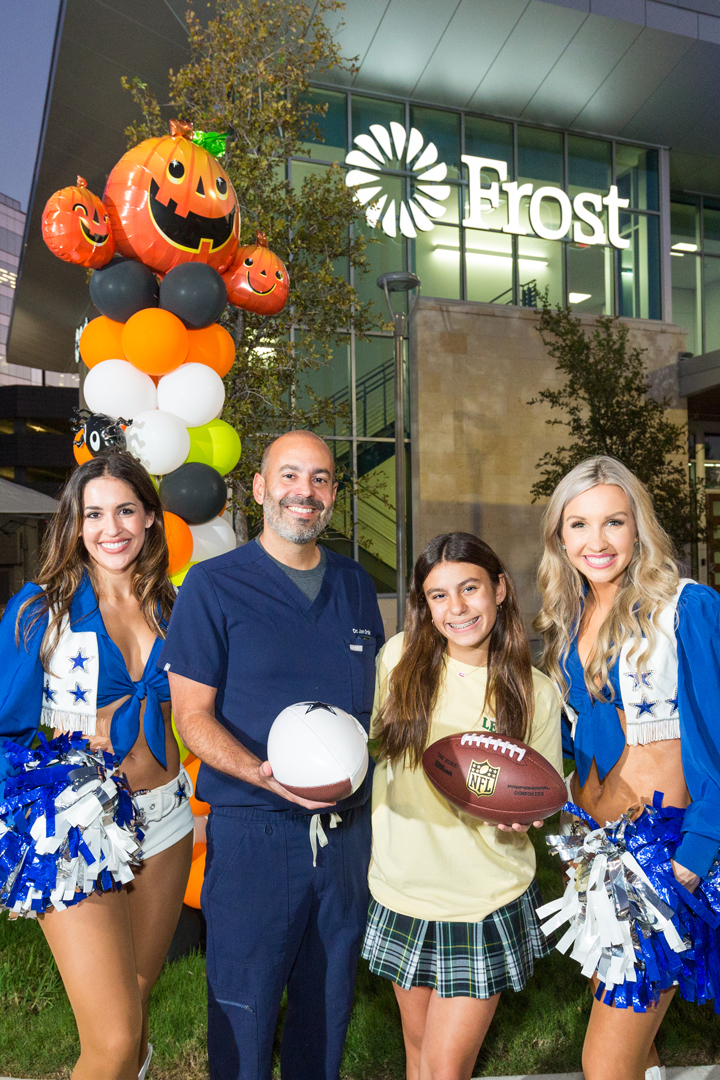 Dr Ortiz poses with his daughter and the Dallas Cowboys Cheerleadrs